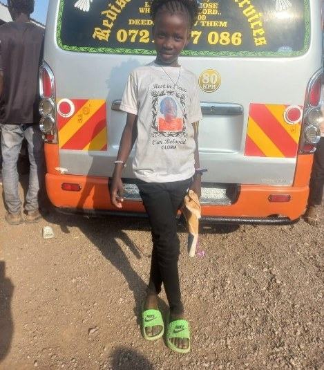 Abigael standing with her hands together, wearing a T-shirt printed in memory of her sister Gloria